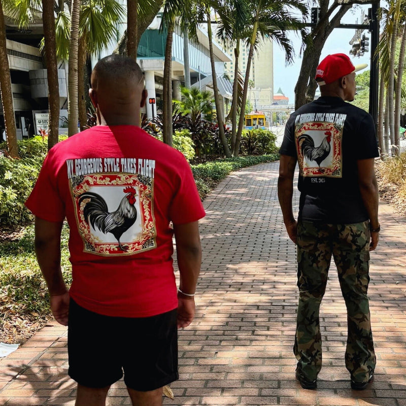 Two men walking on a path with rooster designs on their shirts.